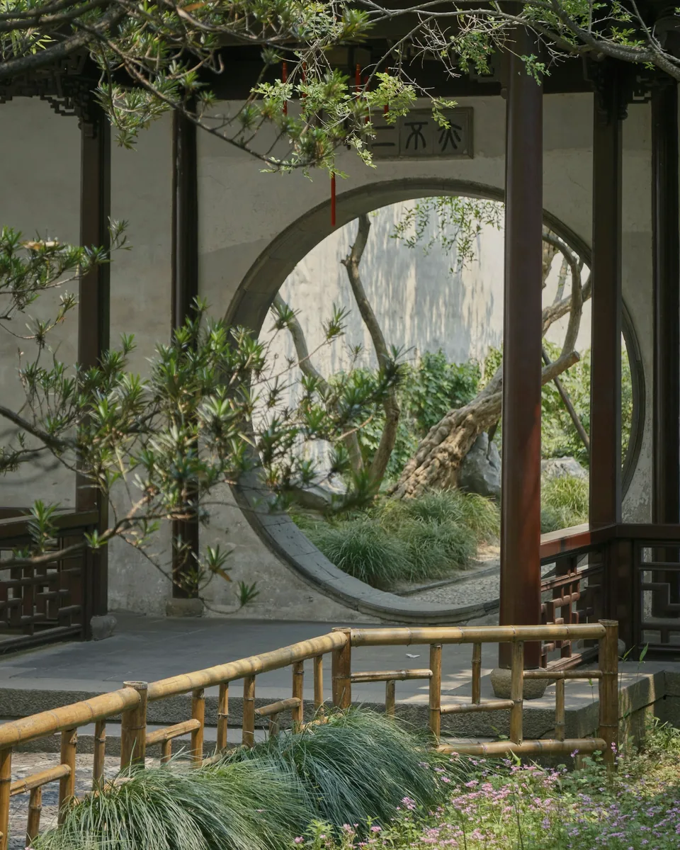 Porte ronde dans un mur blanc, ouverte sur un jardin chinois bordé de bambous